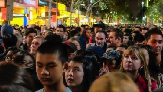 A crowd of people in an urban environment at night.